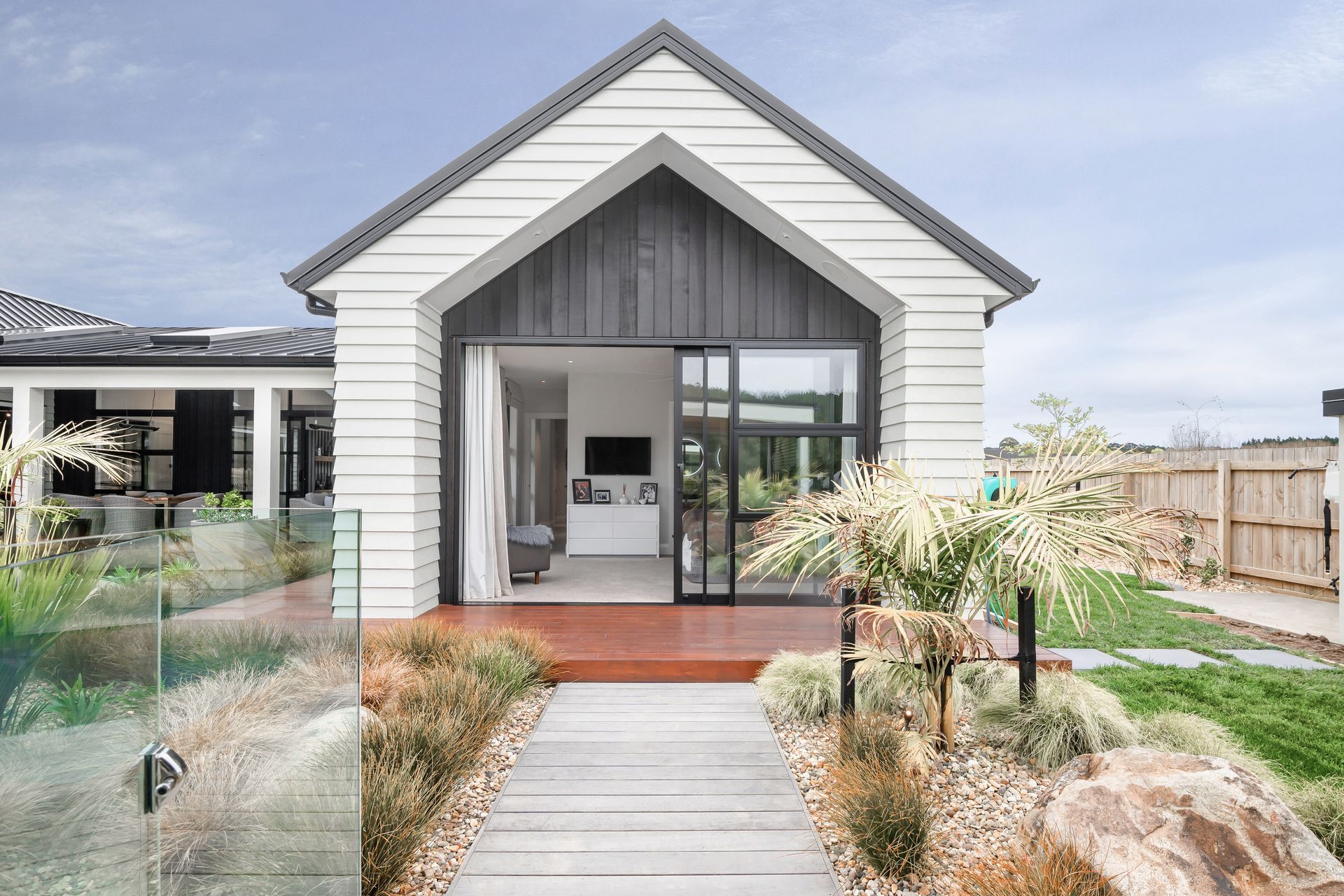 Accents of black vertical cedar within jutting weatherboard frames make a feature of the end walls, marrying beautifully with the bold lines of the Spanlok 380 pan ribbed roof by Roof Industries.