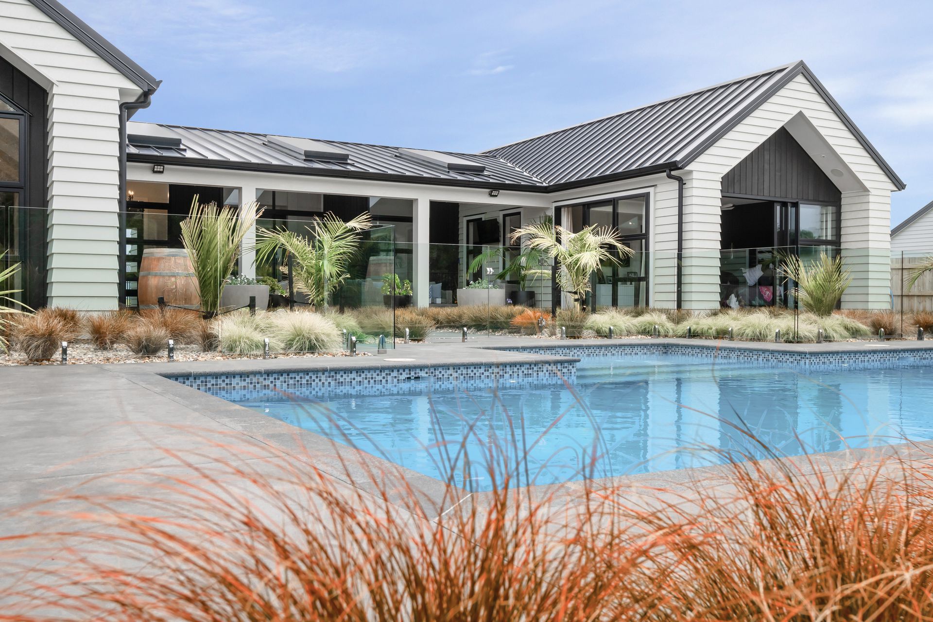 Resort-style landscaping by Green Living Landscaping connects this space to the generous pool, constructed by New Wave Pools.