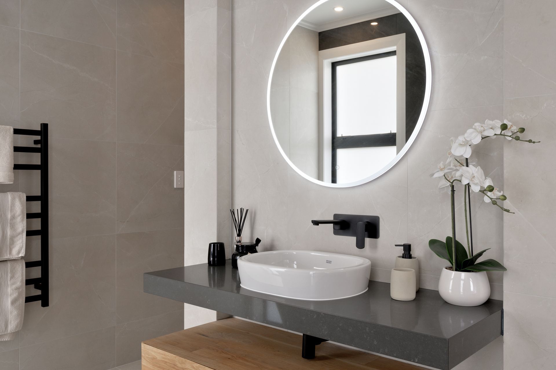 Each bathroom has a mix of stone, tiles, timber and black accents.