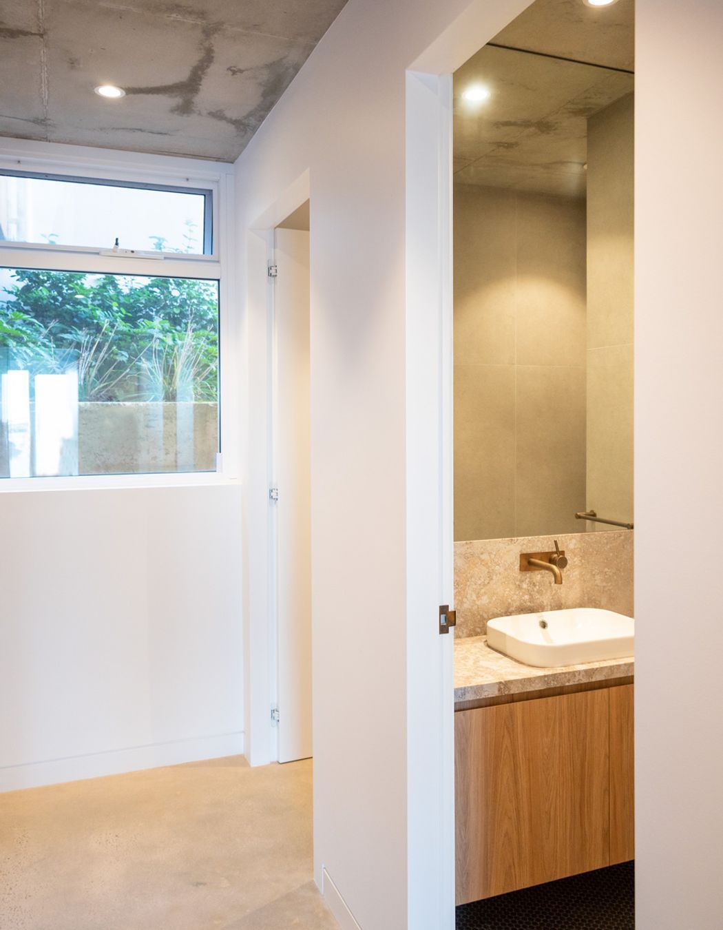 The hallway leading through to the bathroom holds minimal architectural detailing for a modern look.