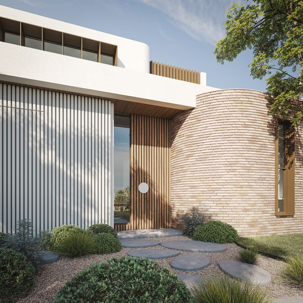 Contemporary residential facade featuring a curved pale brick wall, crisp white rendered upper volume, vertical timber screening, dark-framed glazing, and a recessed timber entry door. A low-maintenance landscaped forecourt uses gravel, rounded stepping stones, ornamental grasses, and clipped shrubs.
