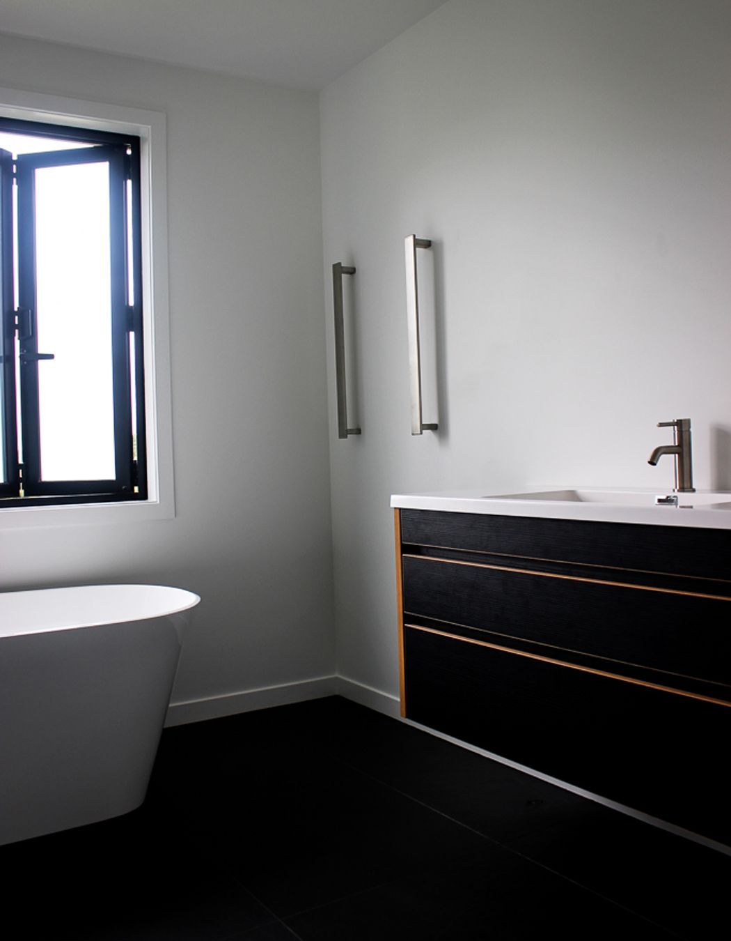 Tiled floors, Black & Ply Vanity and vertical towel rails keep this family bathroom looking contemporary and luxurious. Bathroom hardware supplied by Elite Bathrooms