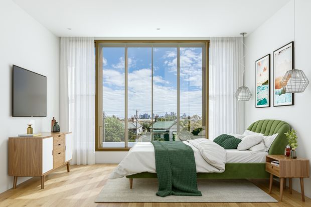 Bright contemporary bedroom with a large floor-to-ceiling window, sheer curtains, green upholstered bed, white bedding, timber mid-century-inspired furniture, pendant lights, framed artwork, and a city view beyond the glazing.