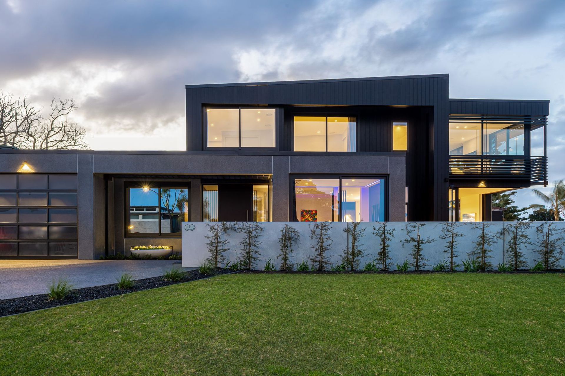 The plan reads as three boxes—a solid, polished black concrete ‘pillbox’ base; a two-storey black vertical timber central element; and, a floating lightweight glass ‘conservatory’ that houses the master suite.