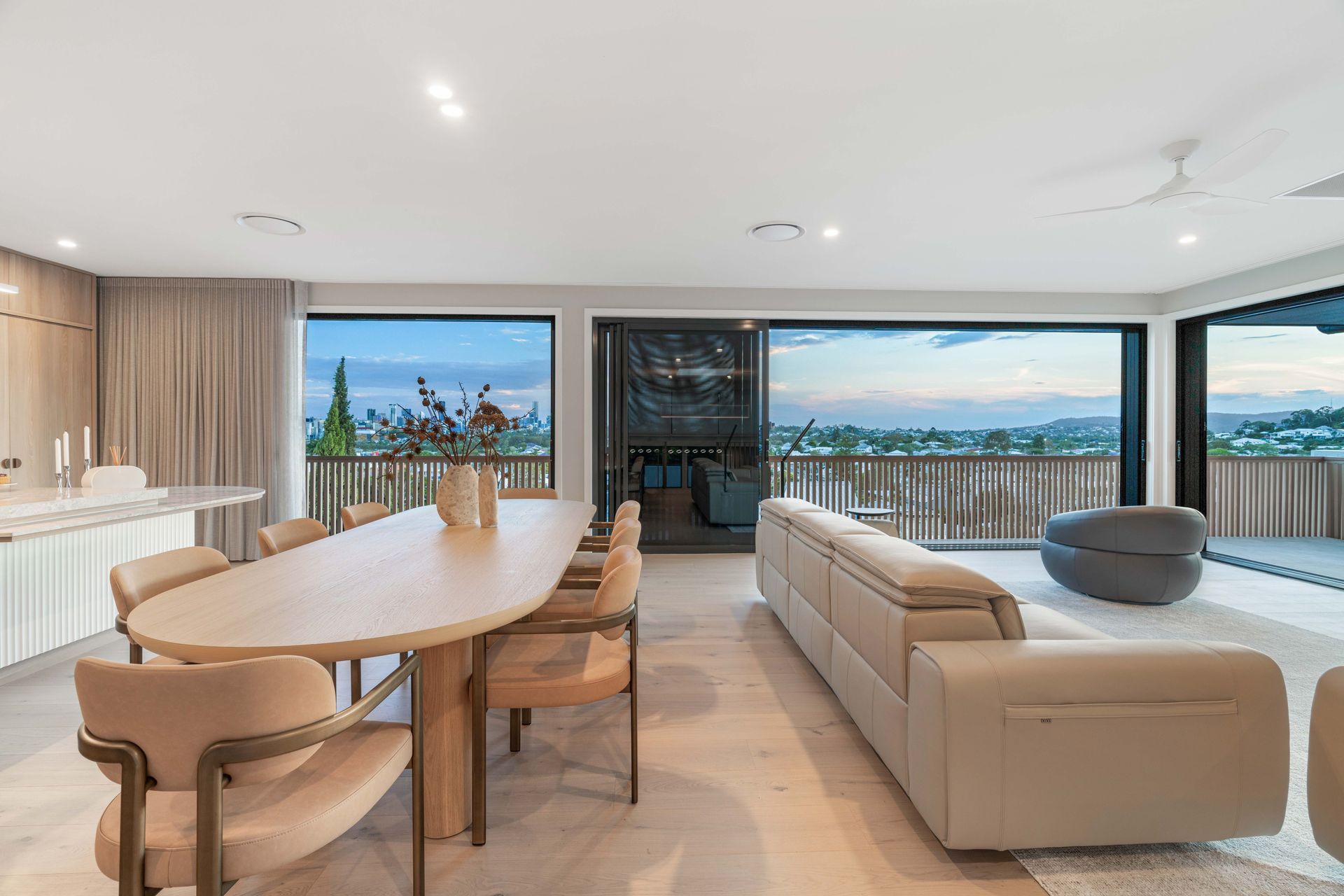 Living and dining share sweeping dusk views over the city from the upper level.
