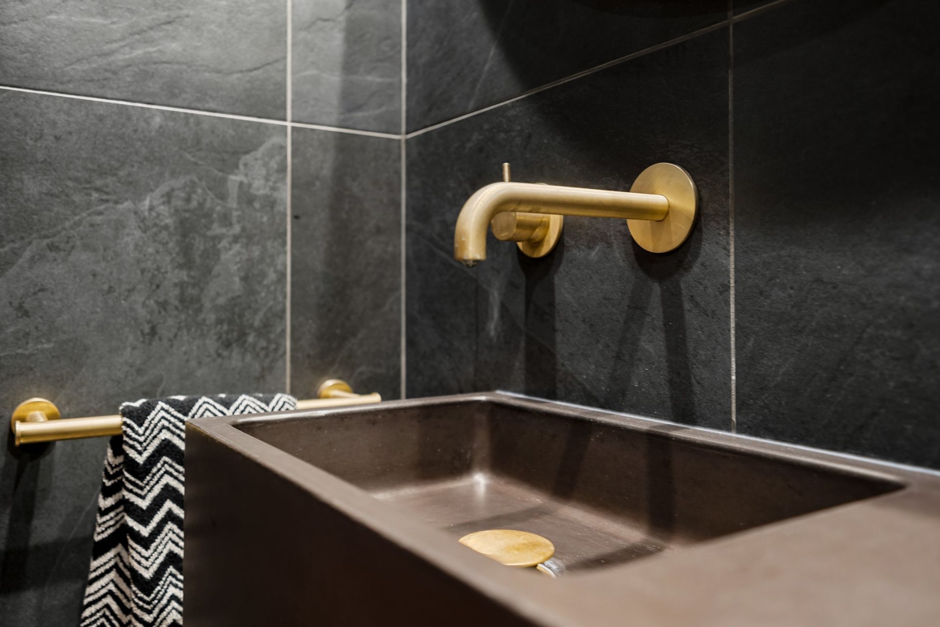 A thoughtfully curated combination features a striking Concrete Nation vanity, complemented by aged brass Progetto tapware and a stylish Missoni (Keith) hand towel, creating a perfect blend of modern design and timeless elegance.