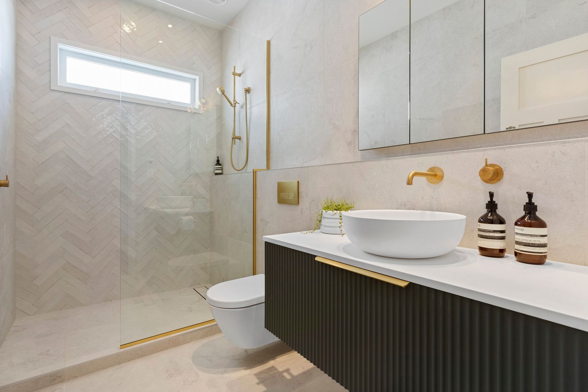 This serene monochromatic palette provides the perfect backdrop for the stunning ‘Kombu’ green fluted wall-hung vanity, allowing it to truly come alive within the space. The rich, textured green hue adds a vibrant pop of color while maintaining a contemporary yet timeless quality that elevates the overall design of the bathroom. This clever juxtaposition underscores the vanity as a striking focal point, infusing the room with character and charm while enhancing its tranquil atmosphere.