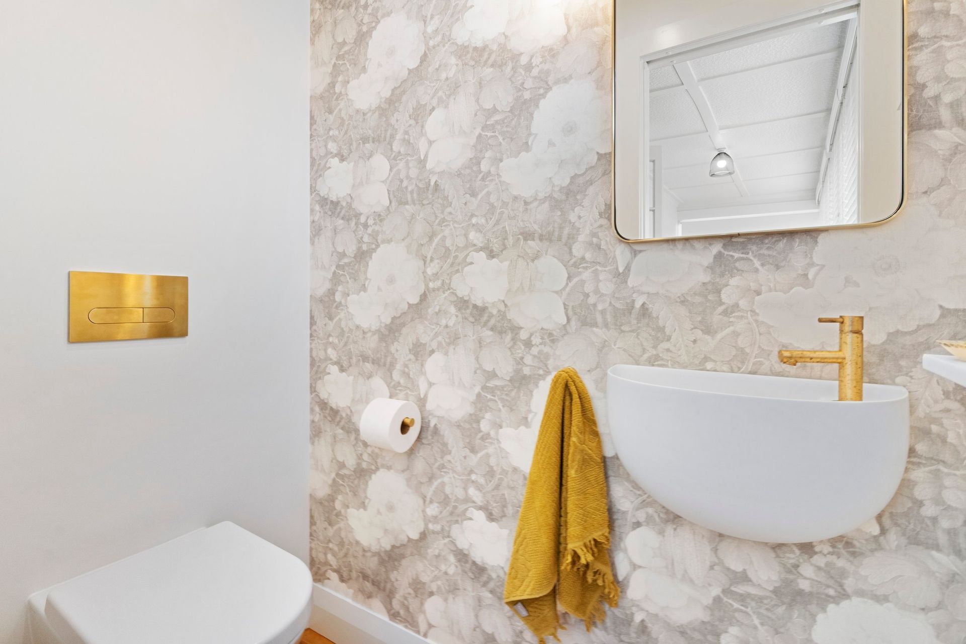 The floral design of this custom linen wallpaper imparts a distinctive and tranquil ambiance to the powder room, transforming it into a serene haven. The delicate patterns and soft colors create a soothing backdrop that enhances the overall aesthetic, inviting relaxation and a sense of peace. This beautiful feature adds character and charm, making the powder room a truly special space where guests can feel at ease.