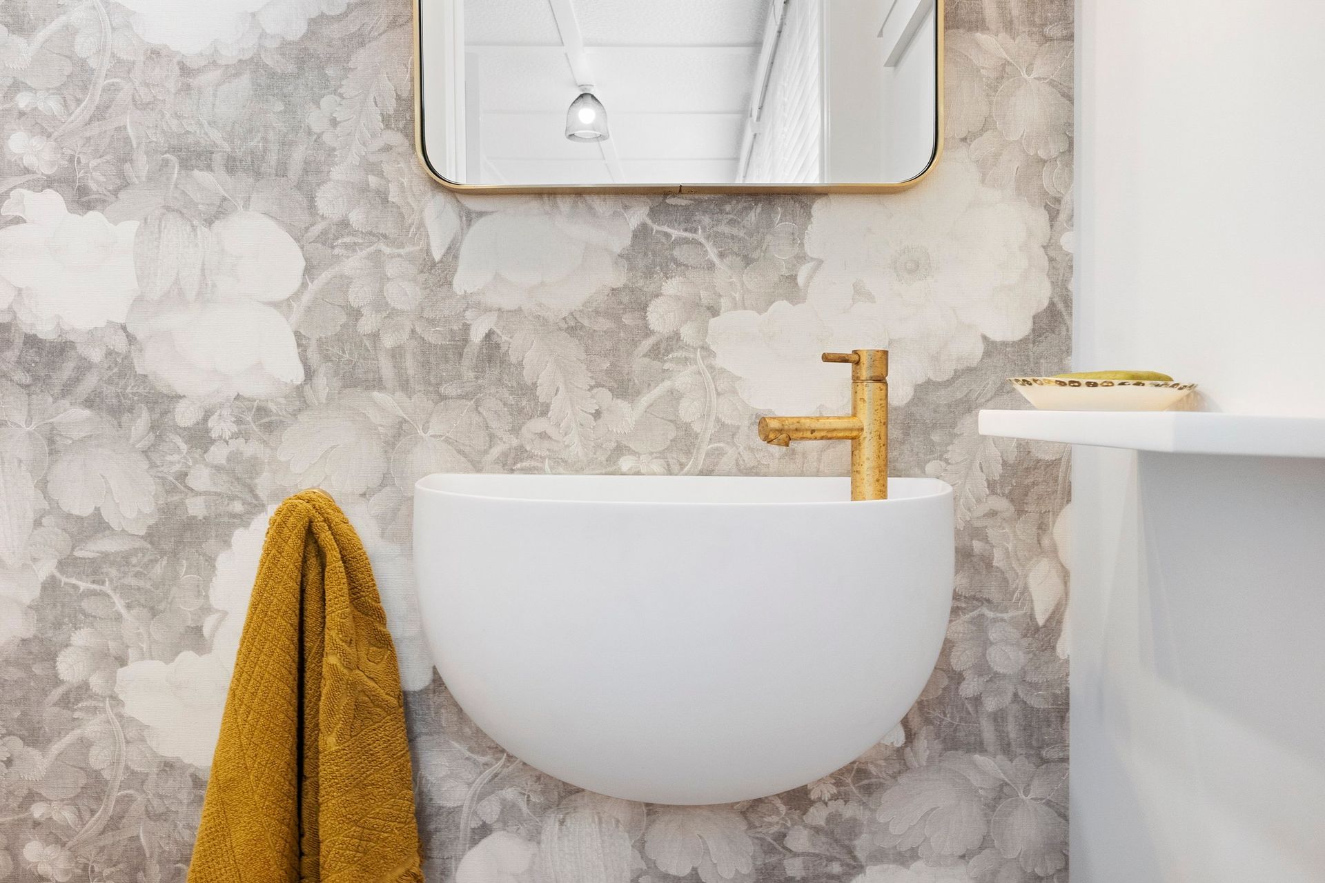 This charming powder room is a delightful blend of elegance and natural beauty, accentuated by the organic brushed brass Progetto tapware that adds a touch of sophistication. The stunning wall-hung Lavamani round basin perfectly complements the space, harmonizing beautifully with the custom linen floral wallpaper. This combination creates a serene and inviting atmosphere, making the powder room not just functional, but also a stylish retreat that reflects refined taste and attention to detail.