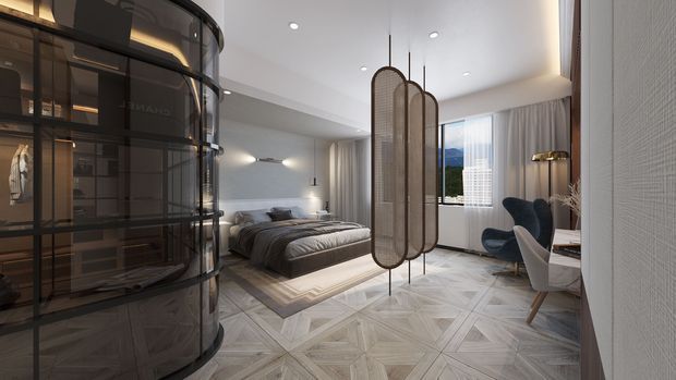 A refined contemporary bedroom with a large upholstered bed, dark built-in curved glass-front wardrobe, patterned light timber flooring, and a sculptural freestanding room divider with woven panels. Floor-to-ceiling curtains frame a bright window, while a small seating area and desk occupy the corner. The palette is neutral and softly lit, with dark joinery and warm metallic accents.