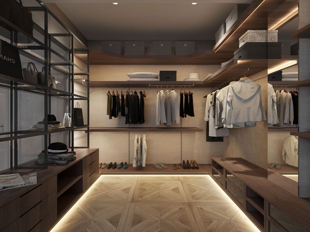 A sophisticated walk-in wardrobe with floor-to-ceiling open shelving, hanging rails, drawers, and integrated display storage. Warm timber cabinetry and shelving are paired with a geometric parquet timber floor, dark metal-framed shelving, and concealed LED strip lighting beneath shelves and cabinetry. Clothing, shoes, hats, and accessories are neatly displayed throughout the room.