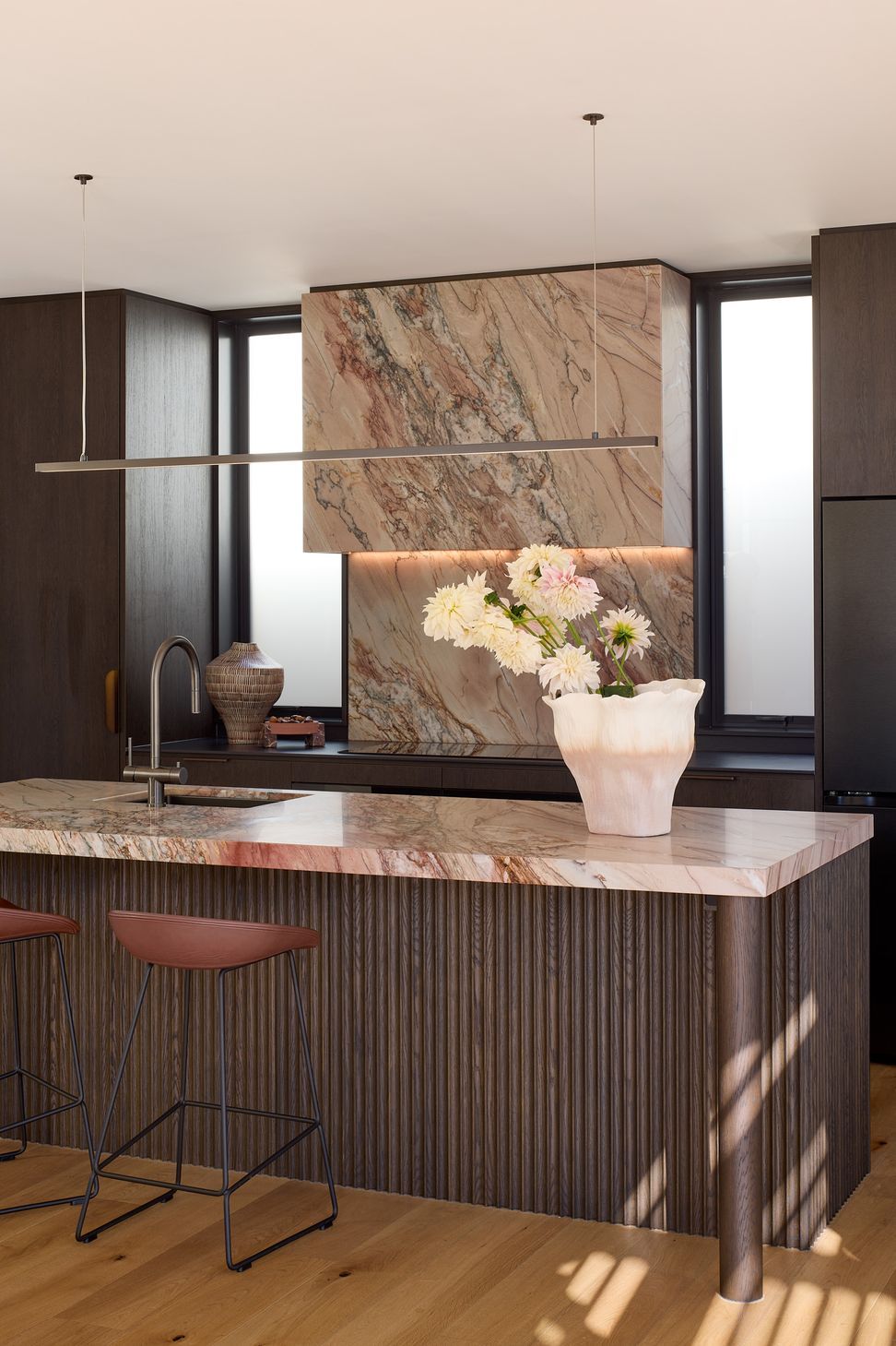 The kitchen is organised around a generous granite island, combining bespoke cabinetry, rich natural materials and thoughtful planning to support modern family living.