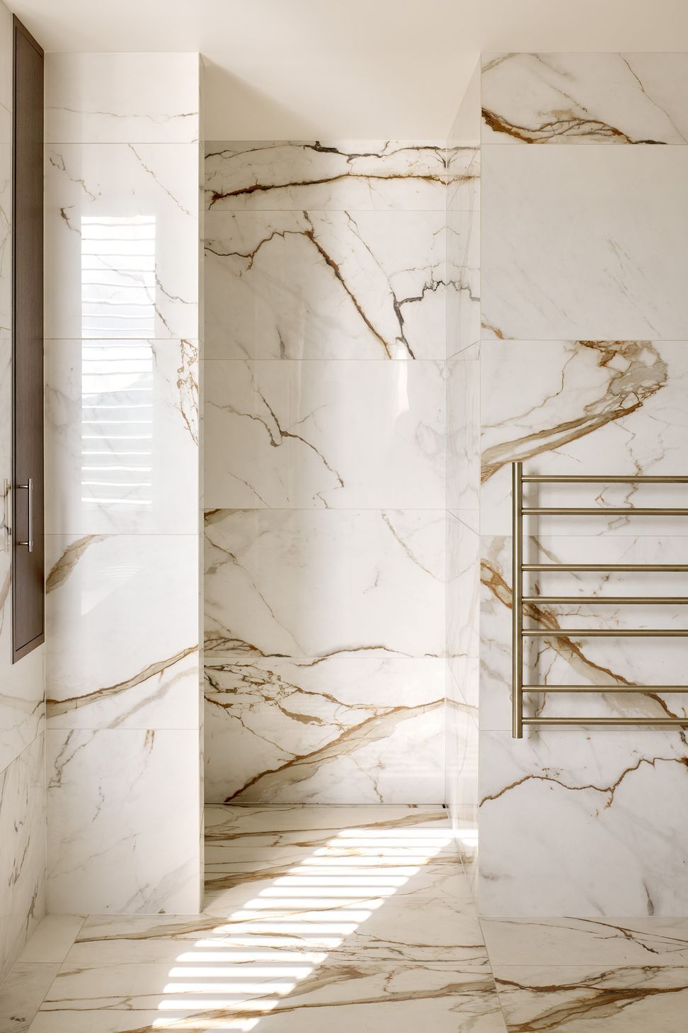Wrapped in marble-look tiles, the ensuite creates a calm and luxurious retreat. A discreet laundry chute is integrated into the dark timber cabinetry, combining everyday functionality with carefully considered detailing.