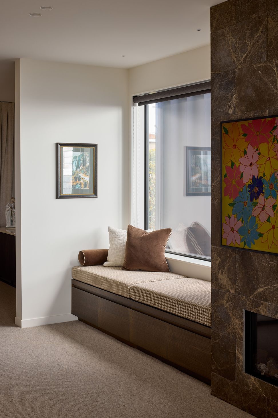 The living room is anchored by a substantial stone-clad fireplace and integrated built-in seating. The natural stone introduces warmth and texture while creating a strong architectural focal point within the open-plan interior.