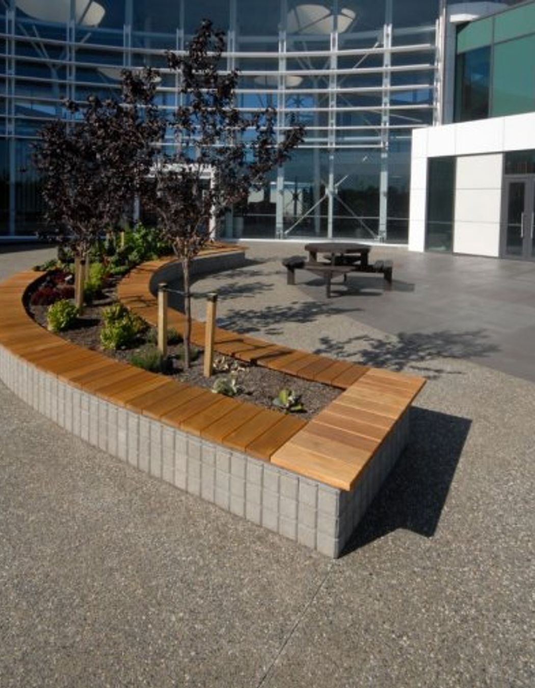 Exposed aggregate Otautahi with 10% white stone and Holland Set pavers honed in Charcoallaid vertically as the base for the planter box and seating