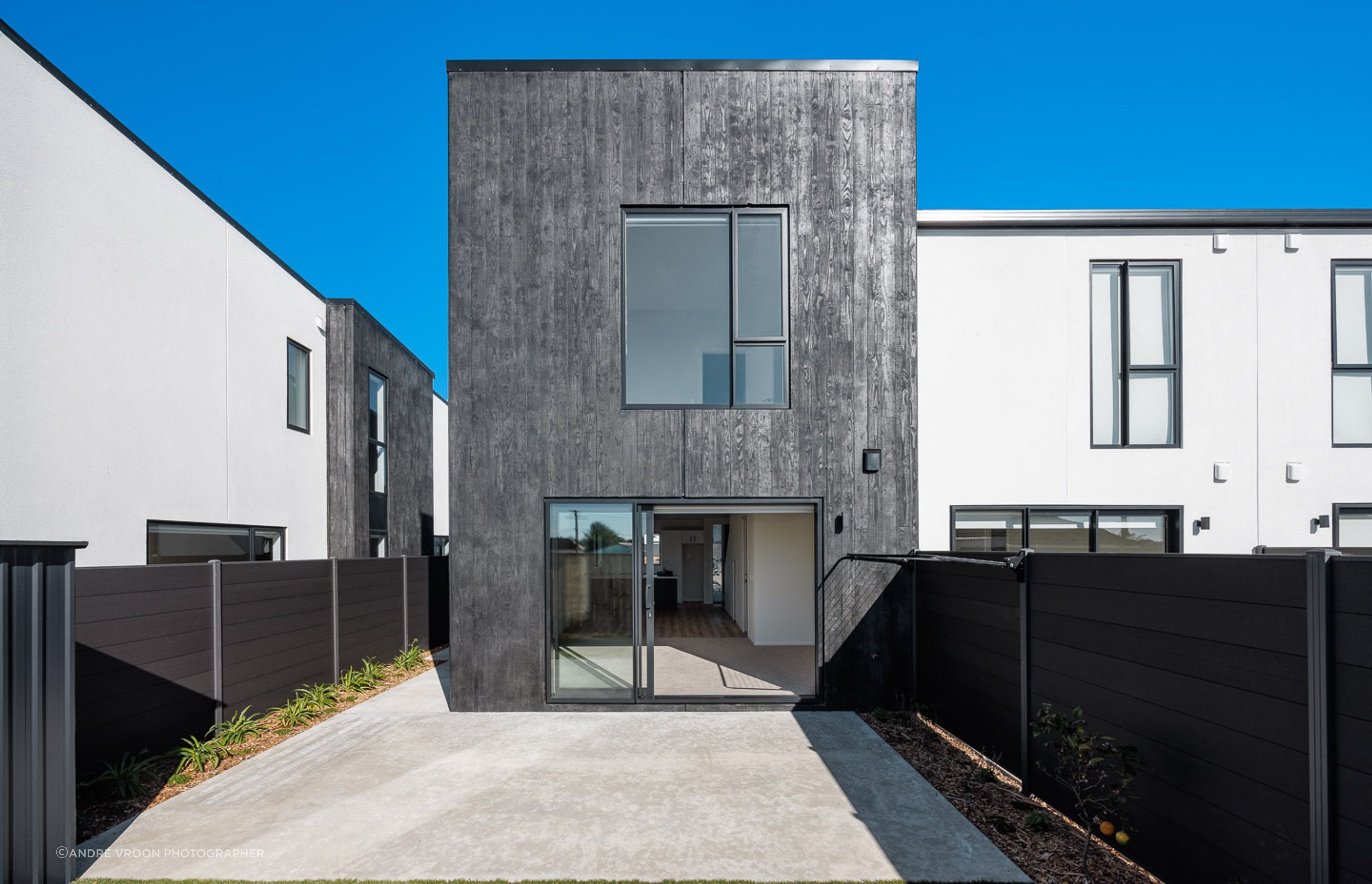 Dark tinted timber board-formed precast concrete contrasting with the smooth white panels