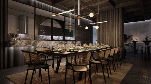 A sophisticated contemporary dining room or restaurant interior with a long dark dining table, woven cane dining chairs, elaborate table settings, and sculptural linear pendant lighting. Dark vertically ribbed wall panels, timber-toned ceilings, large black-framed arched glazing, and a dramatic stone feature wall create a moody, refined atmosphere. A bar-height seating area is visible in the background.