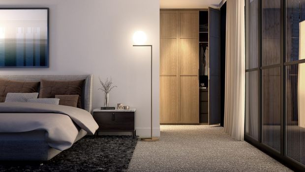 A refined contemporary bedroom with a neatly made upholstered bed, dark bedside table, framed abstract artwork, slim floor lamp, textured dark rug, and full-height glazed wardrobe or partition doors. Warm timber built-in cabinetry and softly lit open shelving create a calm, luxurious atmosphere, while sheer curtains soften the large window or glazed wall.