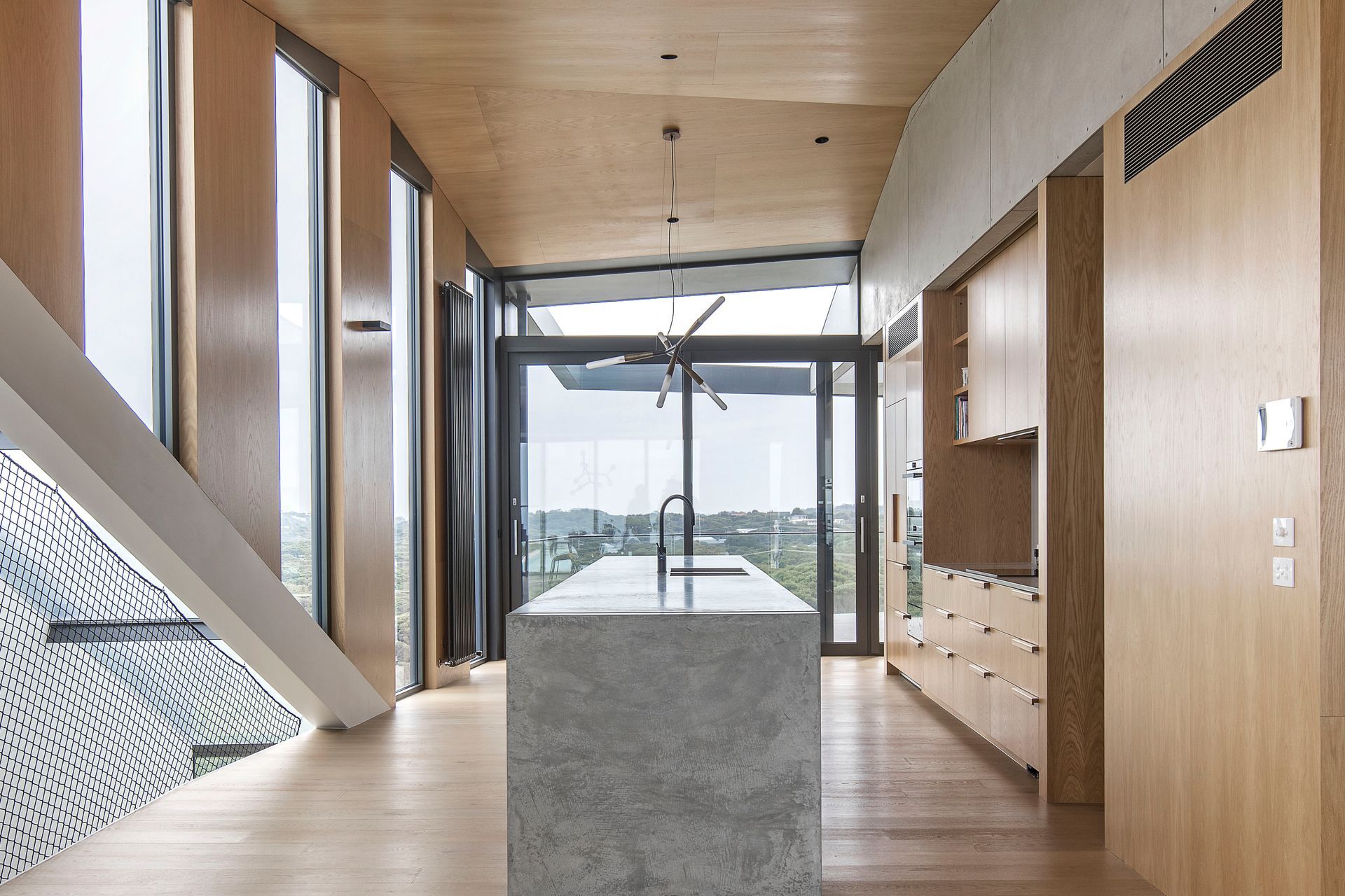 High angled ceilings elevate the kitchen space, framing expansive views of the coastal landscape