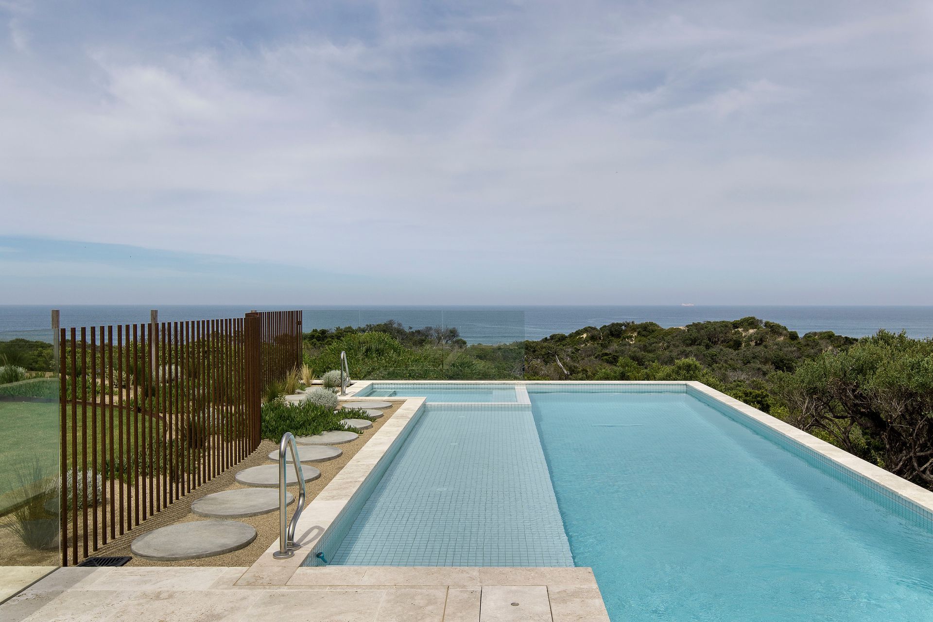A white-tiled pool integrates seamlessly with the rugged edge of the Mornington Peninsula National Park