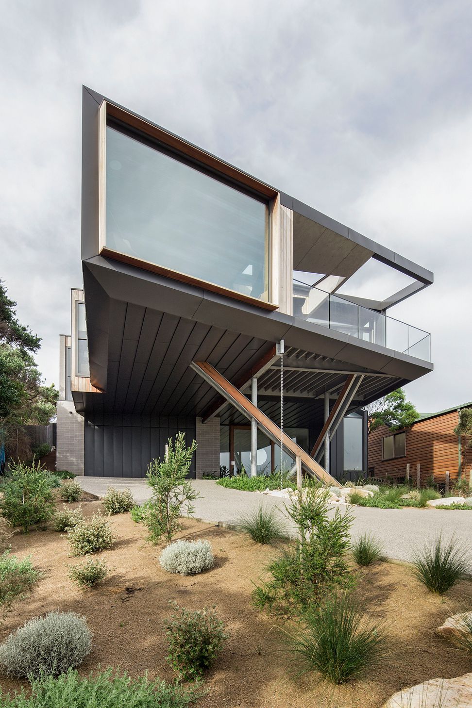 The elevated home appears to float over the arrival sequence, creating a sheltered entrance protected from wind and rain