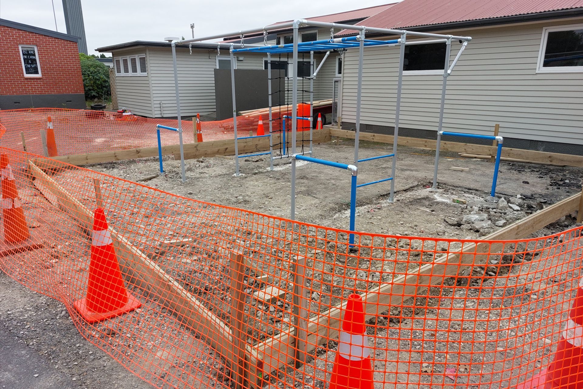Monkey bars being erected and bolted to the foundation, image also shows timber profile being constructed to hold the bark chips inside.
