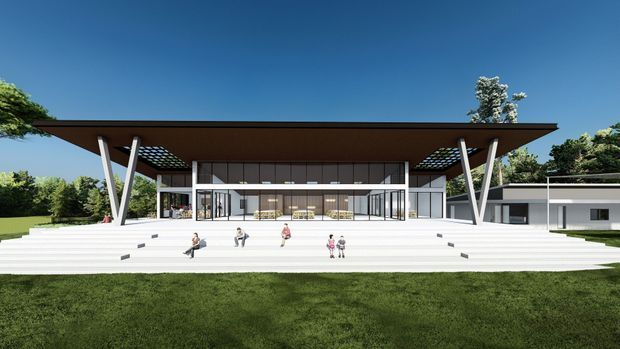 Architectural rendering of a large, low-profile modern pavilion-like residence or public building set in a landscaped lawn. The design features a broad projecting flat roof with deep eaves, dramatic angled support columns, extensive floor-to-ceiling glazing, a wide stepped terrace, and connected single-storey wings. The central glazed volume appears to contain an open living or gathering space, while small human figures provide scale.
