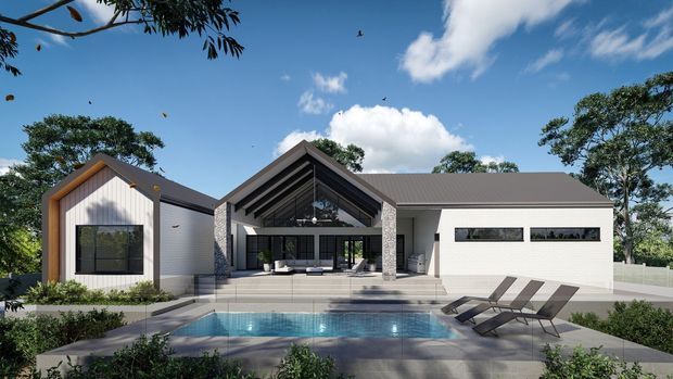 A contemporary single-storey residence viewed from the pool terrace. The composition features a central gabled entry and covered outdoor living area, flanked by light-coloured wings with dark pitched roofs, extensive glazing, and a rectangular swimming pool with sun loungers in the foreground. Landscaping and mature trees surround the home.