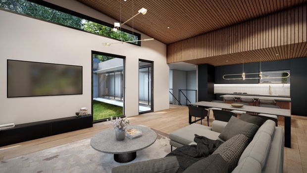 A contemporary open-plan living room and kitchen with warm timber flooring and a slatted timber ceiling. The room features a large sectional sofa, round coffee table, wall-mounted television, dining table, sculptural pendant lighting, and a linear kitchen with dark cabinetry and a light benchtop. Full-height glazing and internal courtyard views bring in greenery and natural light, while a stairway is visible beyond the kitchen.