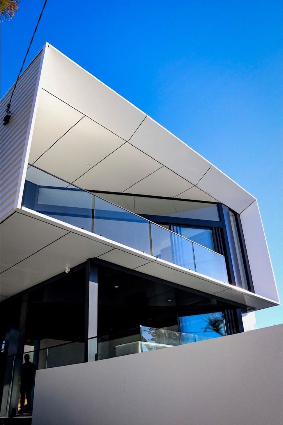 Kruger Residence - Exterior. Angular white roof wrapping the glazed upper level.