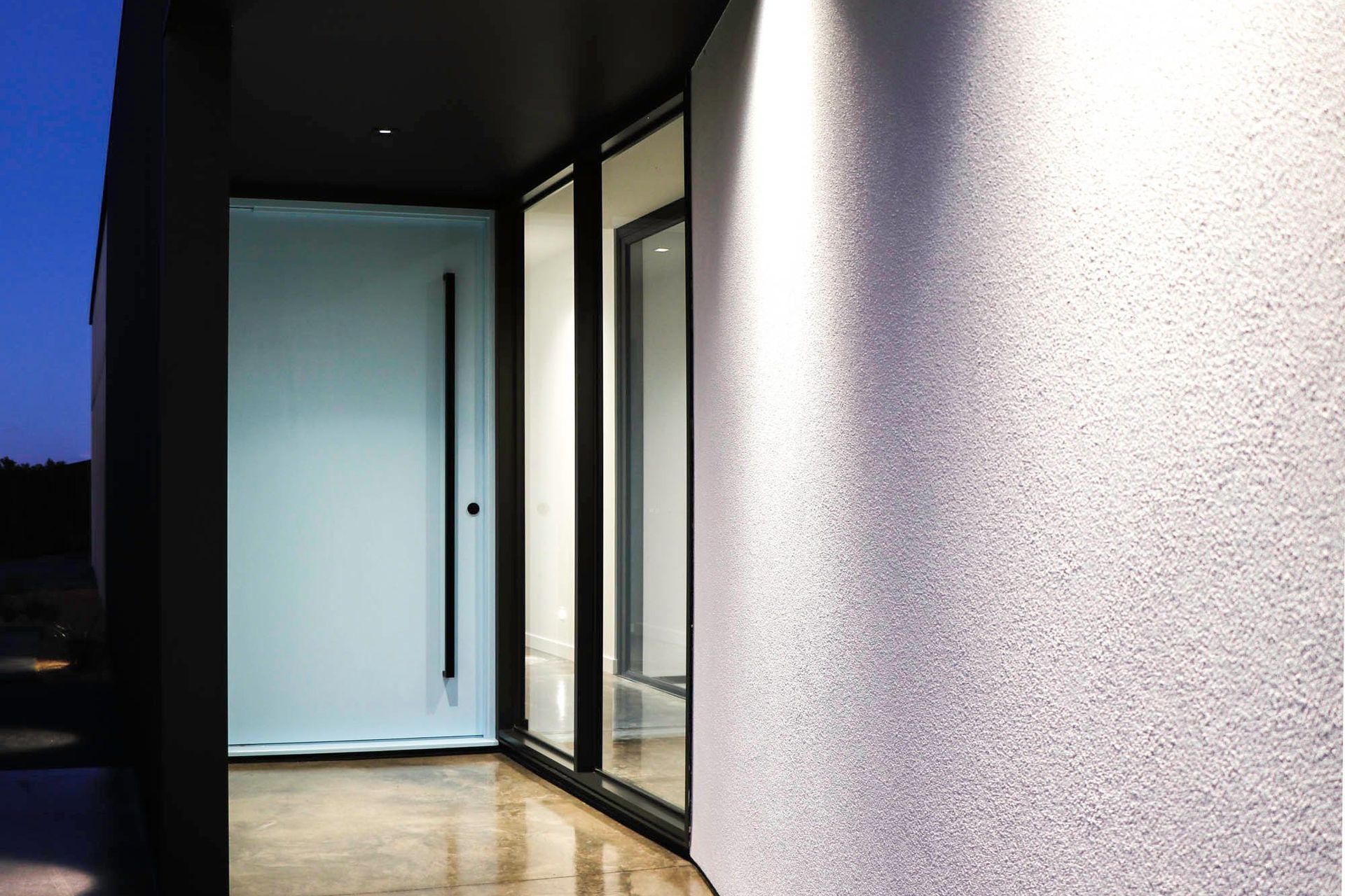 Seabrook and Borg Residence - Entry. Pale blue entry door beside a rendered wall.