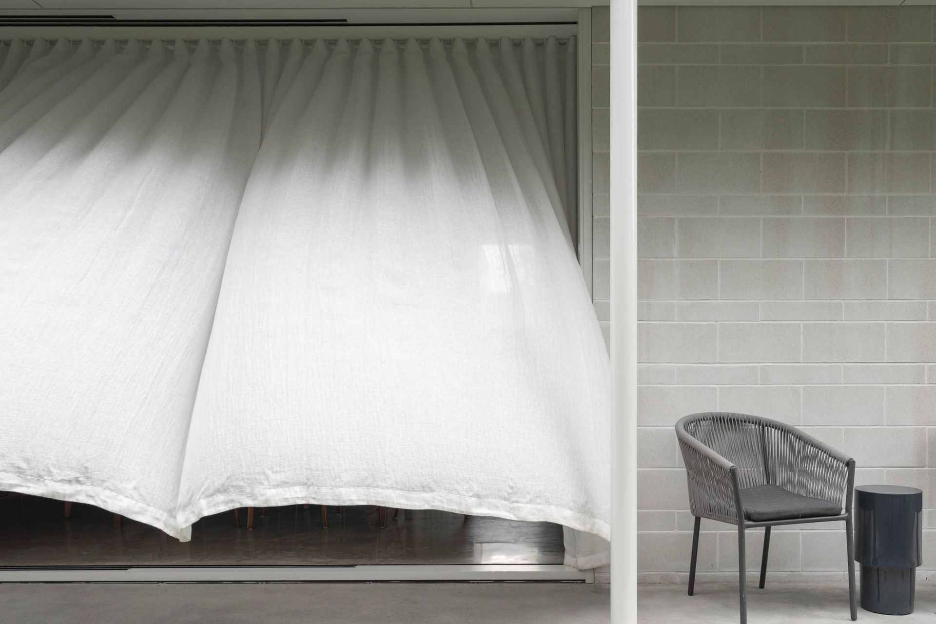 Eleutheria - Patio. Sheer curtains billowing around an outdoor chair.