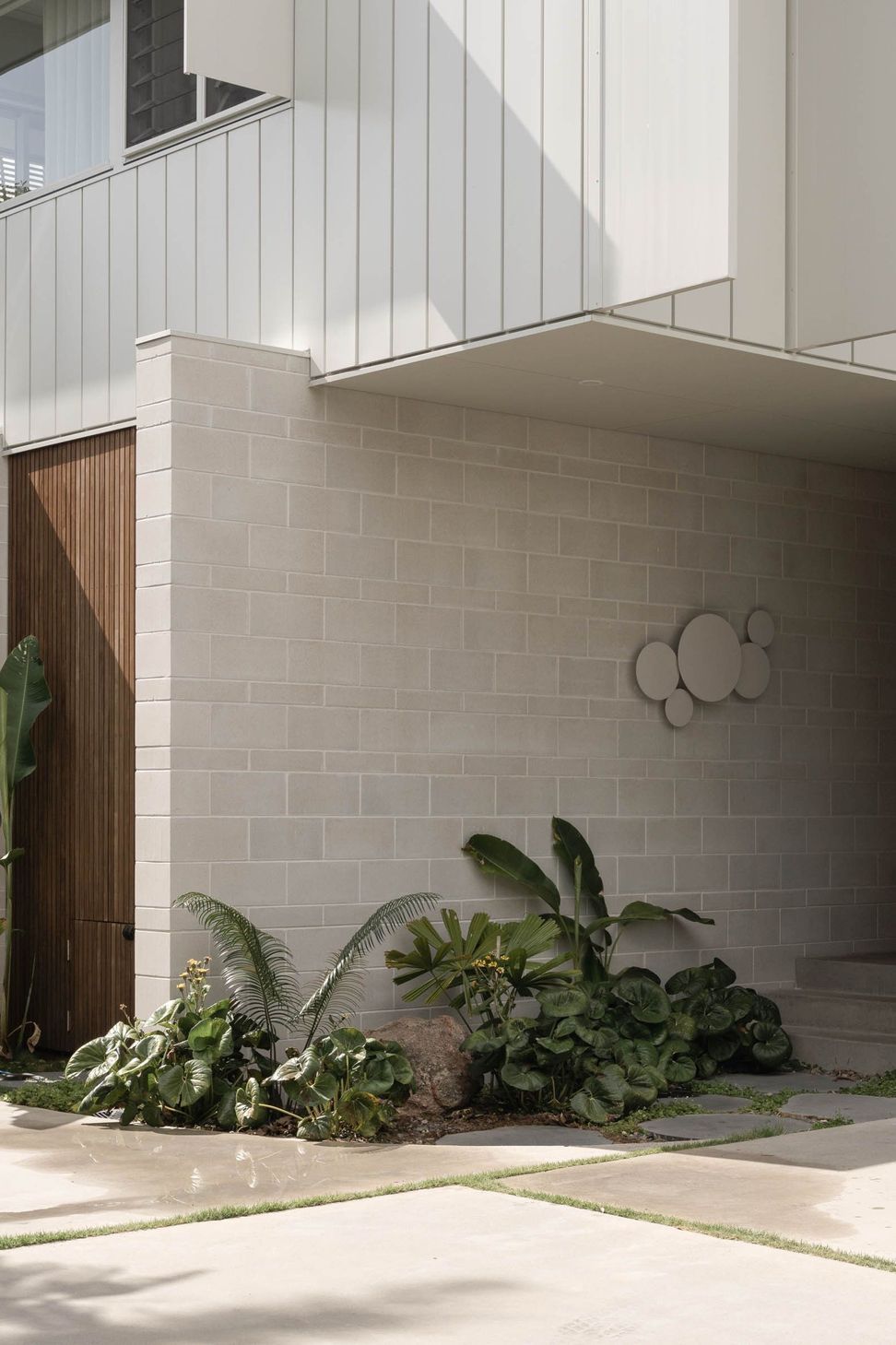 Eleutheria - Entry. Block walls and a timber door with sculptural wall lights.