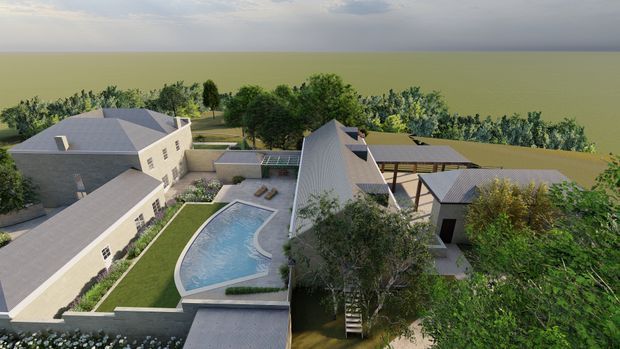 Aerial architectural rendering of a large low-rise residential estate arranged around landscaped courtyards and a curved swimming pool. Multiple pitched-roof buildings with light masonry walls and grey roofing surround paved terraces, lawns, mature trees, and covered outdoor structures. A broad open landscape and water-like horizon extend beyond the property.