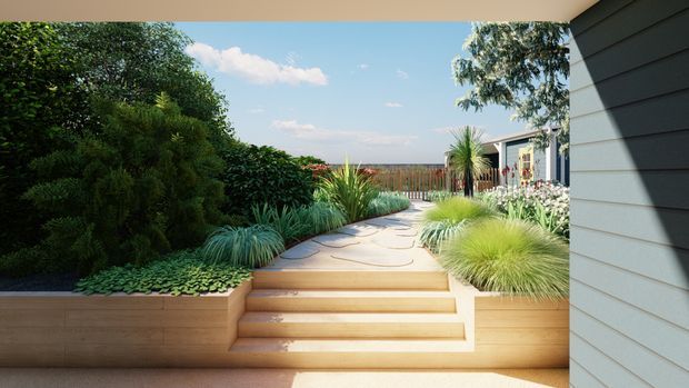 A bright landscaped courtyard or garden viewed from beneath a covered exterior overhang. Wide timber-clad raised planters frame broad timber steps leading to a curved paved path, with layered ornamental grasses, shrubs, palms and flowering plants. A grey horizontal-clad building wing with glazed doors or windows borders the right side, while a timber privacy fence and blue sky are visible beyond.