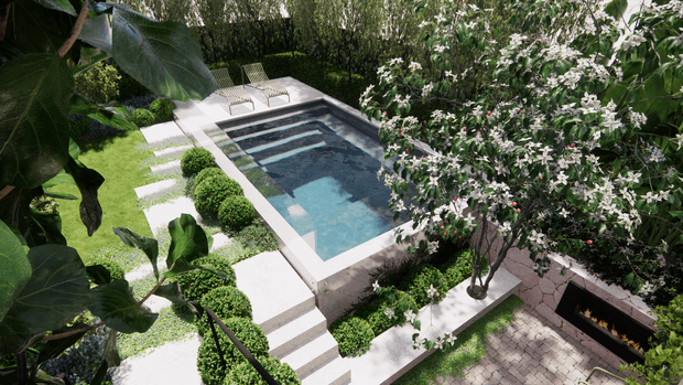 Elevated view of a landscaped backyard pool area with a rectangular swimming pool, broad pale paving, stepped access, clipped spherical shrubs, flowering trees, dense greenery, and a built-in linear outdoor fireplace set into a paved terrace.