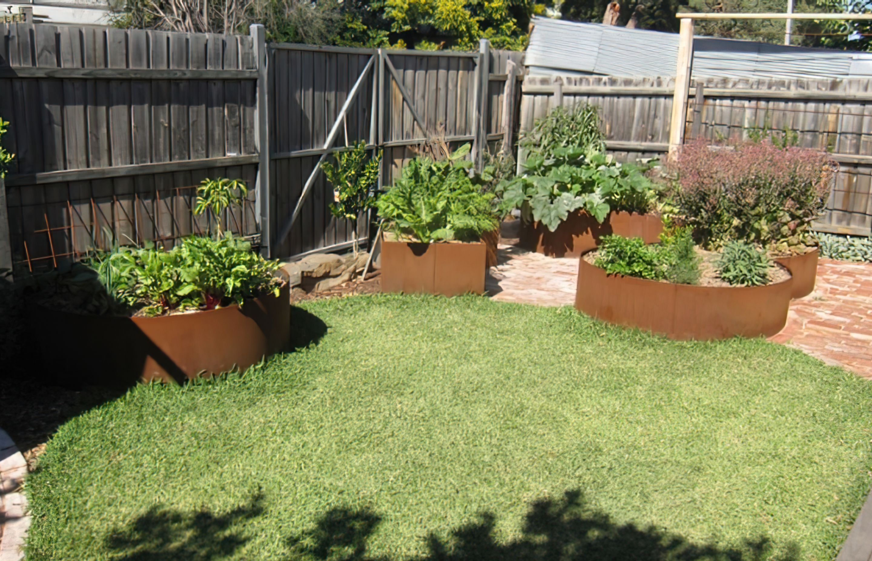 AFTER the garden design. The veggie zone is created using rusted steel raised beds in an organic arrangement