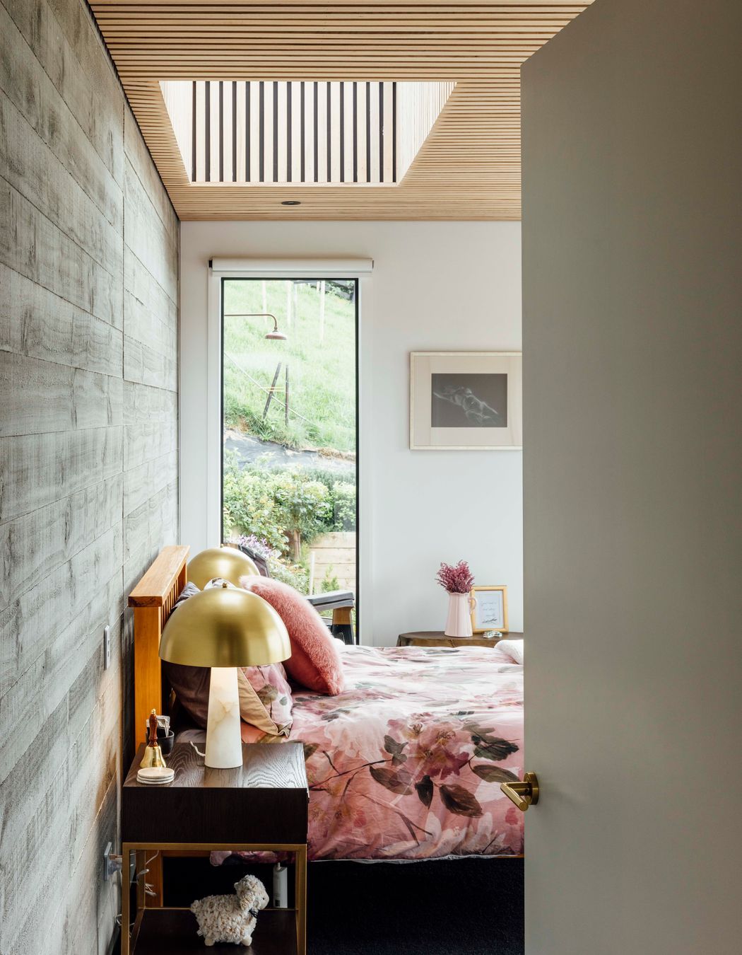 A roughsawn, timber-finished concrete wall in the main bedroom and ceilings clad in American ash battens bring texture to the material palette.