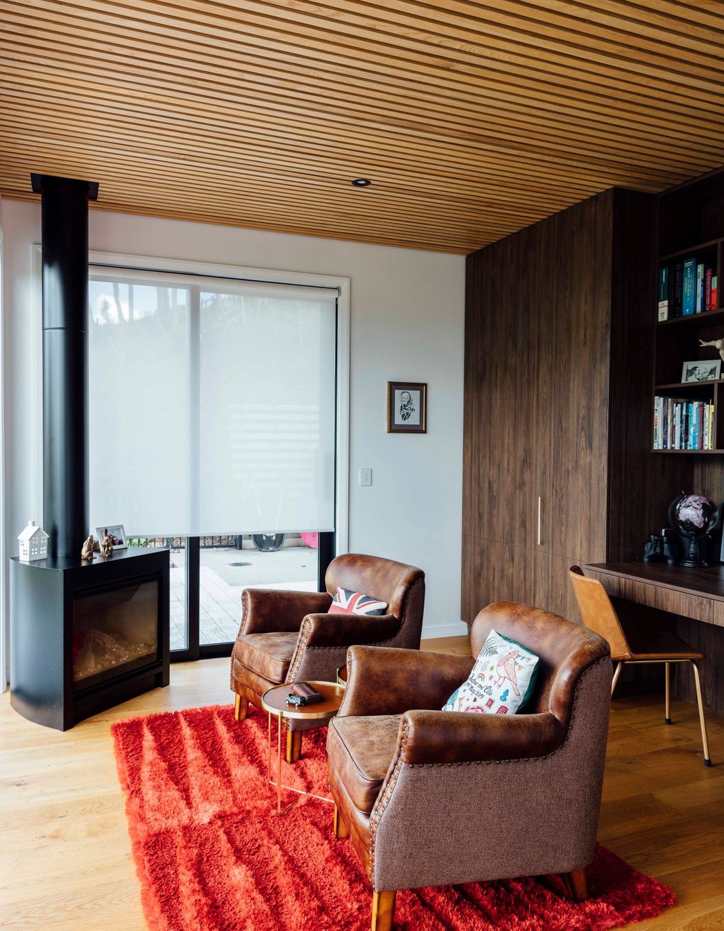 Vintage chairs within the reading room accompanied by a cozy fireplace and contrasting ceilings.