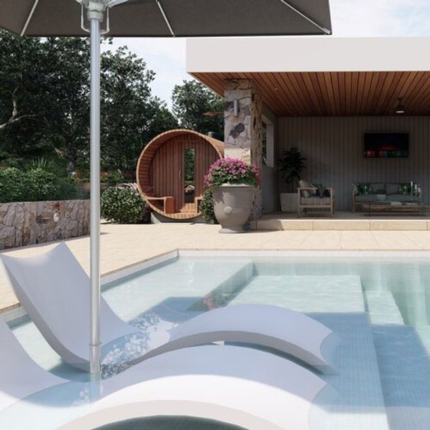 A contemporary poolside courtyard with a pale tiled swimming pool, sculptural white in-pool loungers, and a large outdoor umbrella. Behind the pool is a covered outdoor living area with a timber-lined ceiling, stone-clad column, neutral wall cladding, seating, and a wall-mounted screen. Lush planting and a rounded timber garden pod add organic detail.