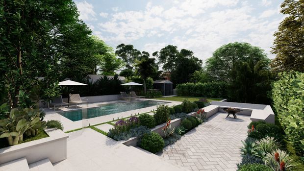 A landscaped residential pool courtyard viewed from an elevated position, with a rectangular swimming pool, surrounding paved terraces, outdoor umbrellas and loungers, raised garden beds, dense tropical planting, and a separate paved entertaining area with a low white built-in bench or wall.