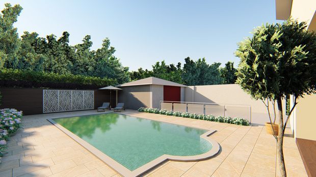 A landscaped residential pool courtyard with a curved-edged swimming pool, pale tiled paving, low rendered boundary walls, planted borders, a dark timber-toned privacy wall with decorative screening, and a small pool pavilion or outbuilding. The scene is bright and contemporary, with mature greenery surrounding the outdoor space.