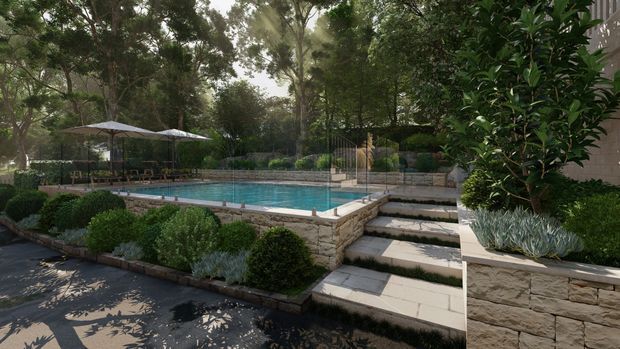 A landscaped residential pool area with a rectangular swimming pool, pale stone retaining walls and paving, broad steps, clipped hedges, ornamental planting, and shaded outdoor seating beneath umbrellas. Mature trees surround the garden, creating a private, refined outdoor setting.