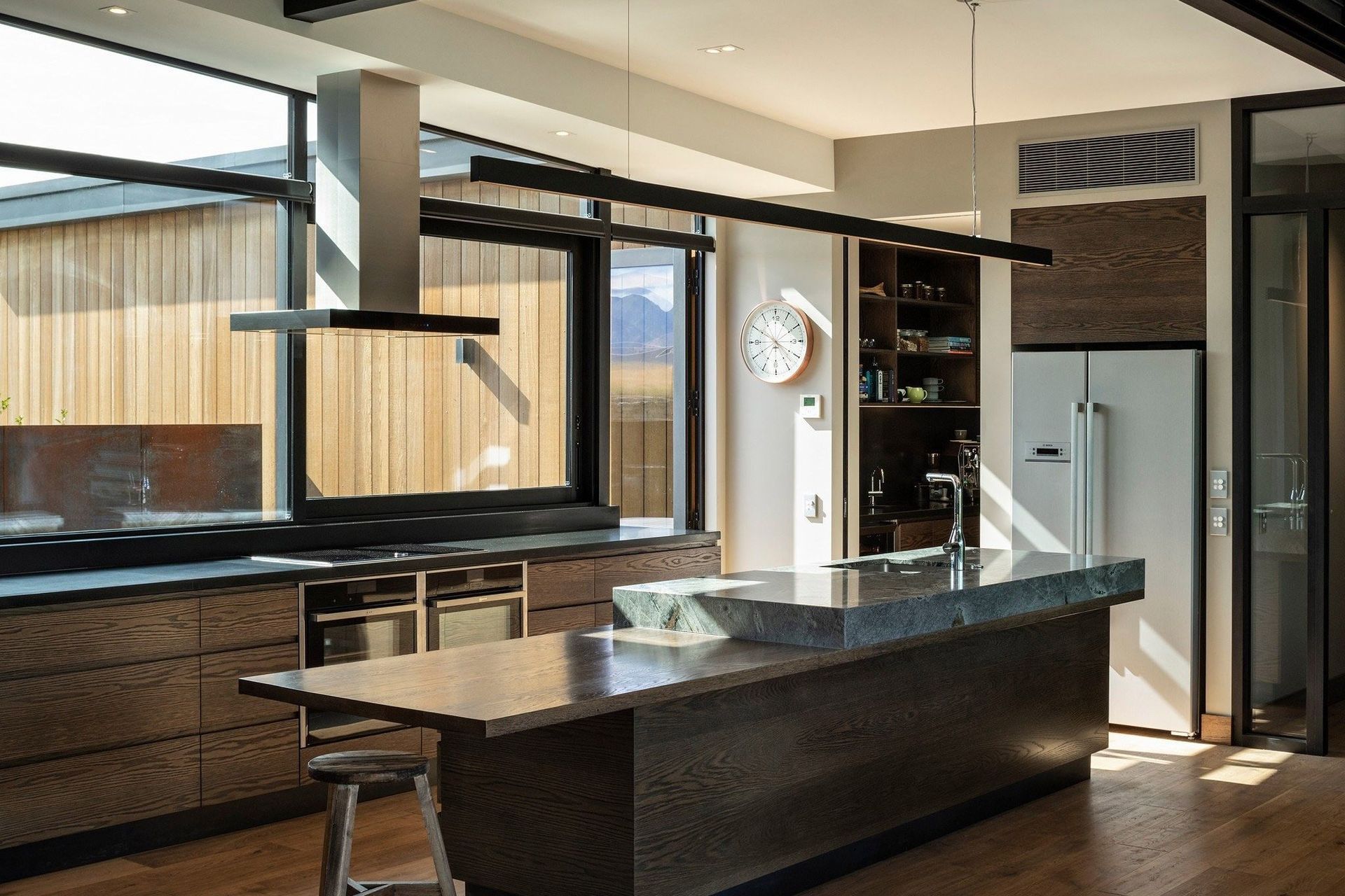 In the kitchen, dark-stained timber cabinetry and floorboards are paired with solid granite benchtops and earthy paint tones to create a warm and comfortable interior that also reflects the strength of the Otago countryside.