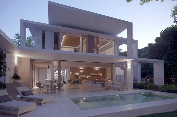Contemporary two-storey residence with crisp white geometric volumes, extensive floor-to-ceiling glazing, and a broad overhanging flat roof. The open ground floor connects an illuminated living and dining area to a paved pool terrace, with minimalist outdoor seating and landscaped surroundings.