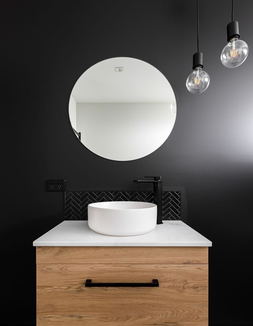 The main bathroom mimics the home's exterior with a dark feature wall.