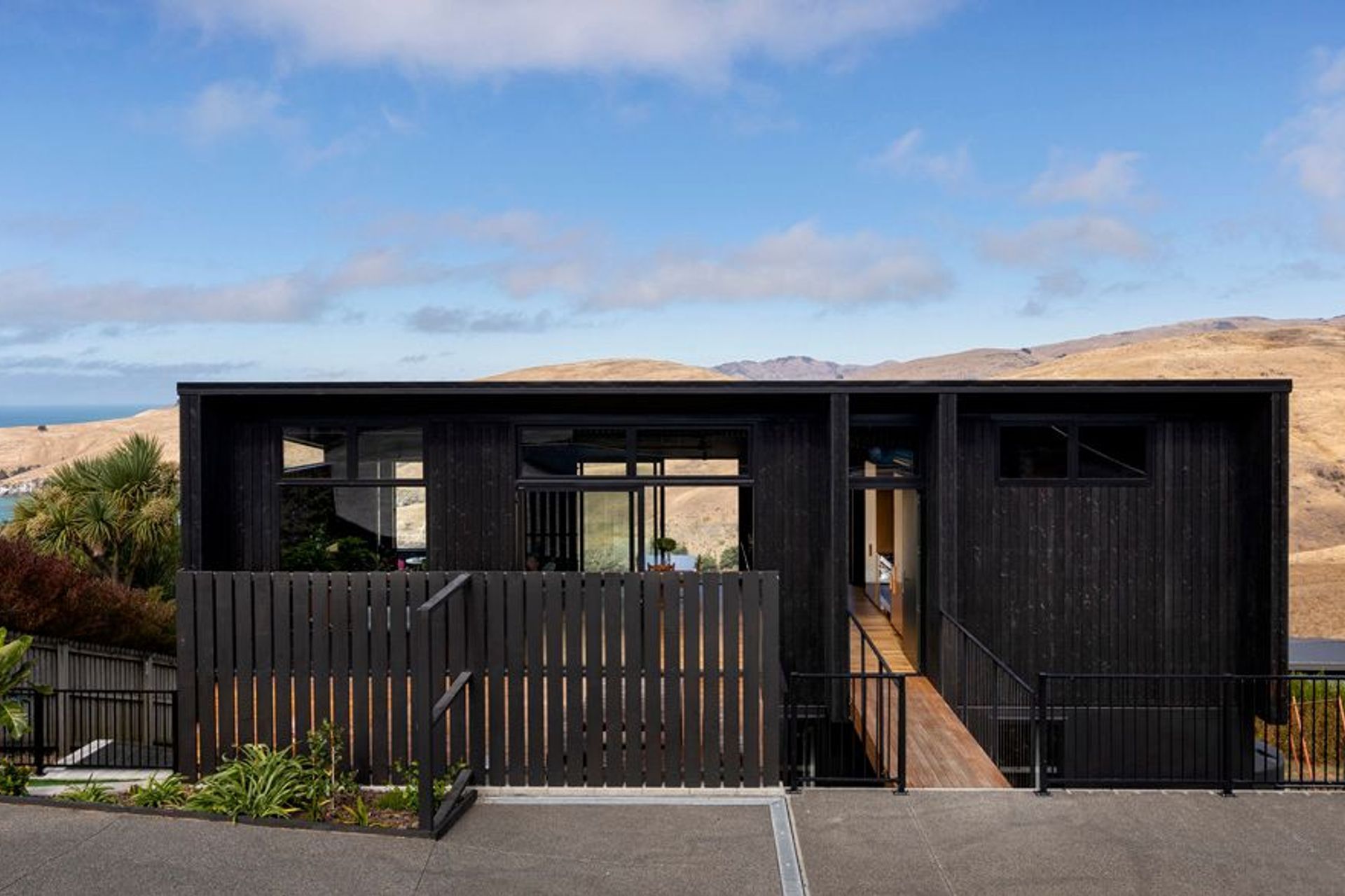 High-level windows on the West-facing facade help admit late afternoon sun into the interior before it sets below the surrounding hills.