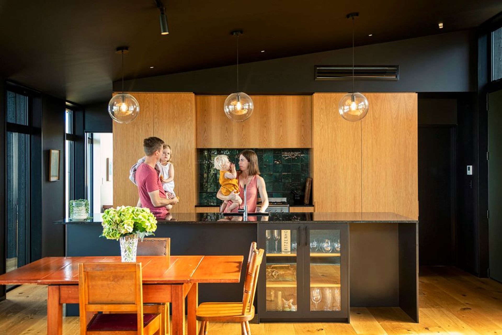 Engineered oak flooring and oak accents in the kitchen add warmth to the otherwise dark colour palette.