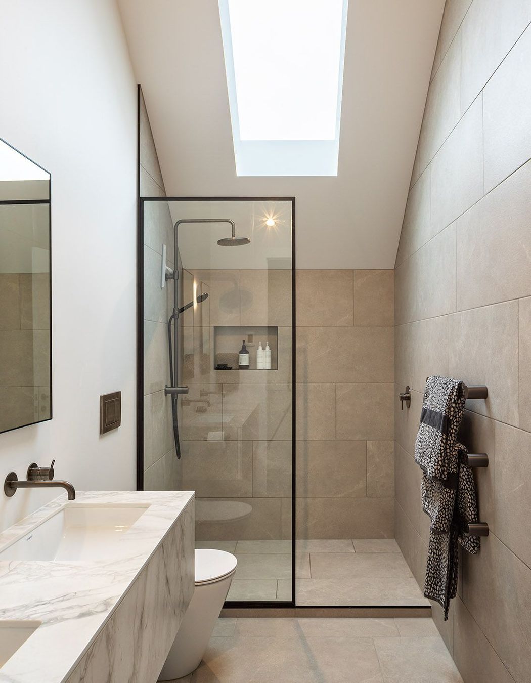 A skylight is cut into the master en suite, cleverly negating the need for a window and illuminating the natural stone palette.