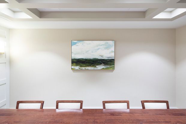 Bright, minimalist dining room with a long polished timber dining table and four simple timber-framed chairs. The room has pale walls, a white coffered ceiling with recessed beams, and a single landscape artwork centered on the wall.